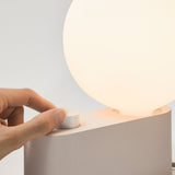 Close-up of Alumina Lamp in Blossom finish with hand adjusting dimmer control on grey background.