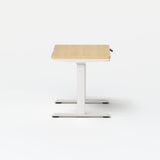 Mini Standing Desk with light oak surface and white adjustable frame shown from side angle