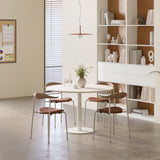 Round meeting table styled in a modern workspace with four chairs, wood shelving, and soft pendant lighting