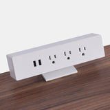 White Urbanica clamp-on desk power outlet mounted on a walnut tabletop, featuring three AC outlets and dual USB ports for seamless desktop charging