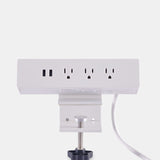 Rear view of Urbanica clamp-on desk power outlet showing secure mounting clamp, power cord, dual USB ports, and three AC outlets