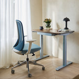 Urbanica Ergonomic Muse Chair paired with a height-adjustable desk in a sunlit home office, showcasing its supportive mesh back, modern armrests, and versatile workspace fit.