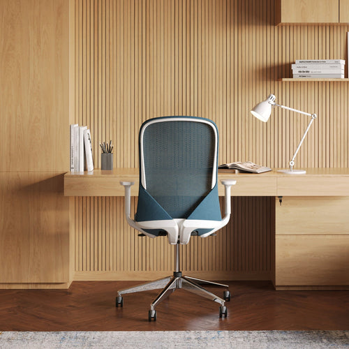 Rear view of the Urbanica Ergonomic Muse Chair in a modern wood-accented home office, featuring breathable mesh back, contoured support, and sleek adjustable armrests for all-day comfort.